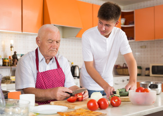 Teenage boy cooking with grandfather