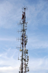 Telecommunications tower, antenna and satellite dish with blue sky at the top of the hill. Communication theme. Wireless technology. 