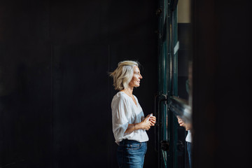 Mature businesswoman looking out window in office