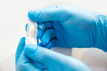 A gloved doctor opens suppositories for anal or vaginal use. Medical candles for the treatment of...