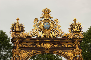 Fototapeta na wymiar A royal crown on top of the golden decorated gilded wrought iron gates Nancy, France.