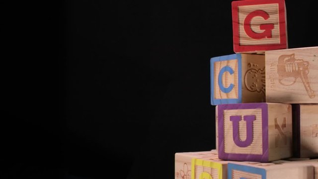Rotating wooden alphabet letter blocks on black background