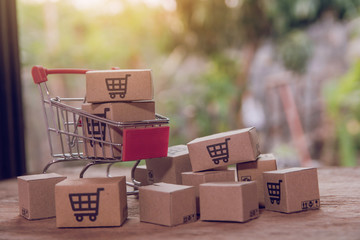 Shopping concept - Cartons or Paper boxes in shopping cart on brown wood table. online shopping...
