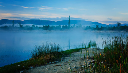 Early morning fog over the lake. Landscape in trendy blue tones.