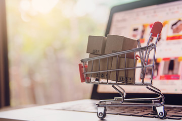 Shopping online concept - Parcel or Paper cartons with a shopping cart logo in a trolley on a...