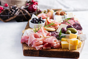 Antipasto platter with ham, prosciutto, salami, cheese,  crackers and olives on a light background....