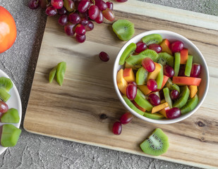 fresh  sliced fruits in salad on the grey background and wood