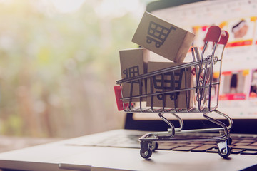 Shopping online concept - Parcel or Paper cartons with a shopping cart logo in a trolley on a laptop keyboard. Shopping service on The online web. offers home delivery..