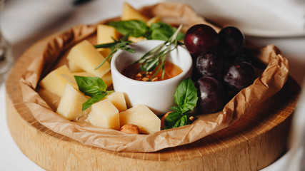 sliced parmesan with grapes and honey on a wooden board