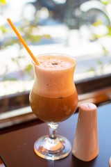 Glass with freddo cappuccino coffee and a cinnamon case next to it.Coffee time concept.