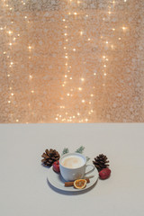 Weihnachtlicher Cappuccino vor Bokeh mit Tannenzapfen, Zimtstange, Orangenscheibe, Apfel und...