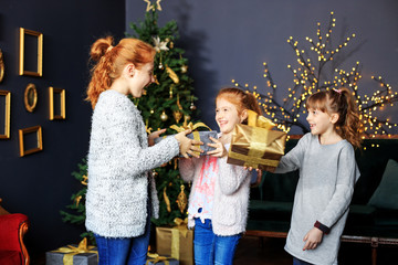 Three happy kids give gifts boxes. Concept of holidays, merry christmas and family.