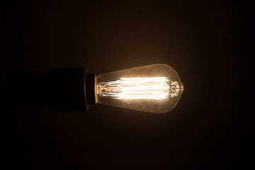 Edison's bulb shines in the dark. black background, place for text. Idea