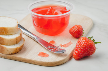 Strawberry jam. Making sandwiches with strawberry jam. Bread and strawberry jam on a white table with jar of jam and fresh strawberry.