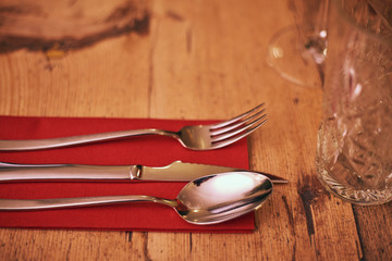 Cutlery on the red napkin on brown wooden table, close up