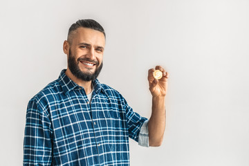 Freestyle. Guy in checkered shirt standing isolated on white holding cryptocurrency coin posing smiling cheerful