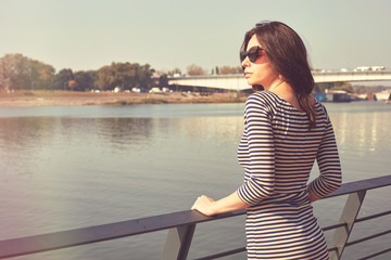 Portrait of beautiful woman in dress enjoying on wooden dock.	