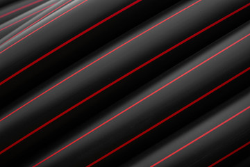 Black rubber or plastic pipes with a red lines as a construction material and equipment at building site. Using as a water pipe.