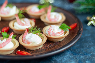 Tartlets with cream cheese and shrimp. Decorated with sprigs of dill and parsley. Seafood.