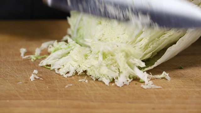 Woman cuts Beijing cabbage with a large knife on a cutting board