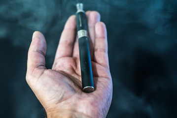 electronic cigarette or vaporizer in hand on black background