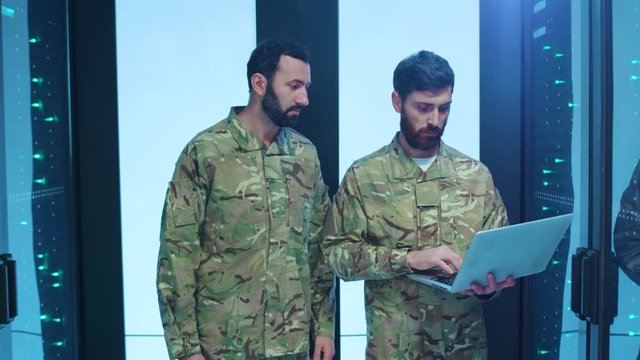 Two soldiers in uniform monitoring a high secure server room of cyberspace. Military men running risky secret operating deactivating power data center running away. Failure.