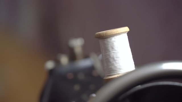 Thread is Wound on a Robbin. Close-up of a Spool with Thin Thread on Working a Vintage Sewing Machine. Spool with thin white thread on working a sewing machine. Sewing bobbin being wound up on a