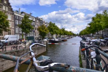 Amsterdam, Holland, August 2019. Parked bikes frame this view on one of the canals. Sunny day with white clouds and blue sky.