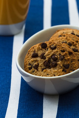 Homemade chocolate cookies in a porcelain plate and a yellow cup of coffee. Closeup.