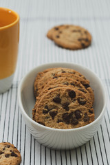 Homemade chocolate cookies in a porcelain plate and a yellow cup of coffee. Closeup. Out of focus background.