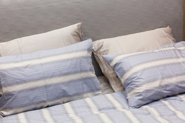 Fototapeta na wymiar Modern bedroom with lightblue curtains and textured cushions.