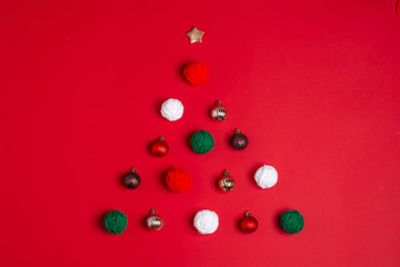 Creative christmas tree made of New years balls and on the red background.