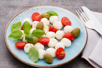Delicious caprese salad with ripe cherry tomatoes and mini mozzarella cheese balls with fresh basil...