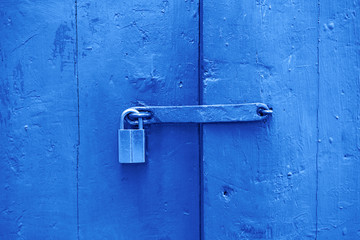 Toned image. Closeup wooden door with lock, old town. Color of the year. Beautiful blue background for design.