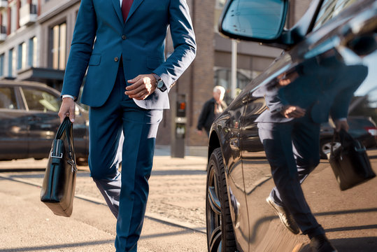 It's only business. Cropped photo of a man in classic suit carrying suitcase while going to his beautiful black car
