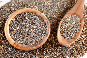 Edible seeds of chia, Salvia hispanica, a flowering plant of the mint family. .Close-up. Chia seeds in a plate of natural olive wood. Product for beauty and health. Proper nutrition. Blurry.