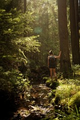Girl standing in a forest in beautiful light with little creek next to her