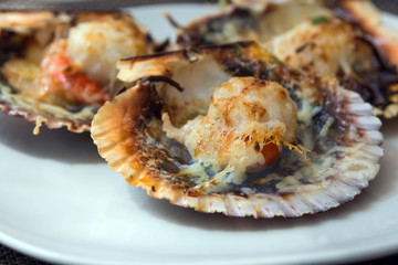 Baked scallops with cheese and spicy sauce. Delicate clam is a real pleasure. Romantic dinner at a Spanish fish restaurant. Mallorca Island, Spain.