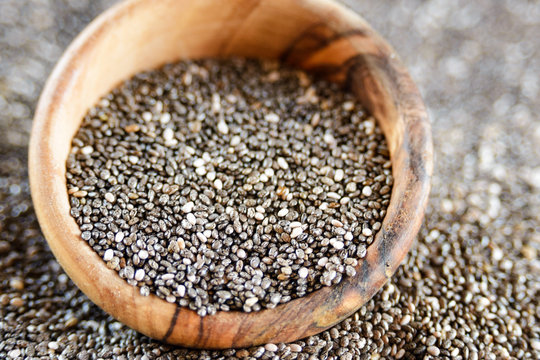 Edible seeds of chia, Salvia hispanica, a flowering plant of the mint family. .Close-up. Chia seeds in a plate of natural olive wood. Product for beauty and health. Proper nutrition. Blurry. © Лариса Люндовская