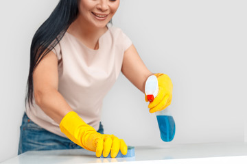 Freestyle. Asian woman in gloves standing isolated on white with spray cleaning surface with sponge close-up smiling joyful