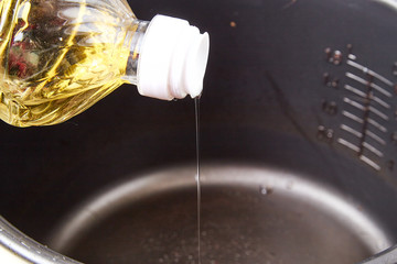 Cooking. A bottle of sunflower oil in the hand and pouring oil into the container
