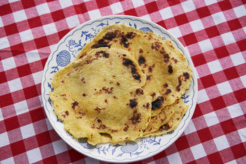 Top view on the traditional simple pancakes made from potatoes and dry fried in steel pan and served on the rustic folk plate. Old and delicious side dish in Czech and Slovakian cuisine called lokse.