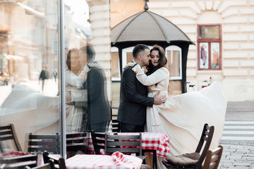 Young couple in good mood sits on the terrace in morning. Pretty woman and handsome man in love. Real love. Happy lovers and family. Happy girl in dress flying in the wind and guy posing in suit.