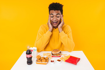 Happy african teenager boy eating fast food meal