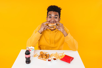 Happy african teenager boy eating fast food meal