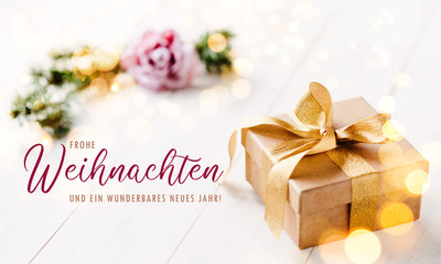 Romantic, golden christmas gift box with bright, light background and feminine, pastel colors / banner, header and elegant greeting text in german language