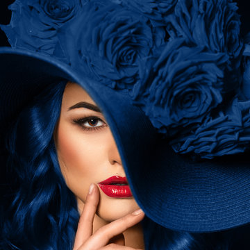 Portrait of a beautiful woman with blue lips in a hat, toned in color of the year 2020, classic blue.