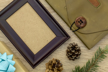 Composition Using Pine Branch, Empty Picture Frame, Men's Leather Handbag, Gift Box, and Pine Cones on Wooden Background