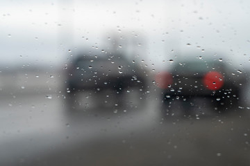 car glass with raindrops and blurred highway on the background