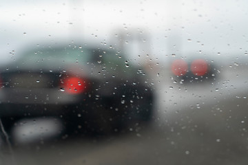 car glass with raindrops and blurred highway on the background